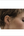 Close-up of a person wearing a gold earring with a plain background