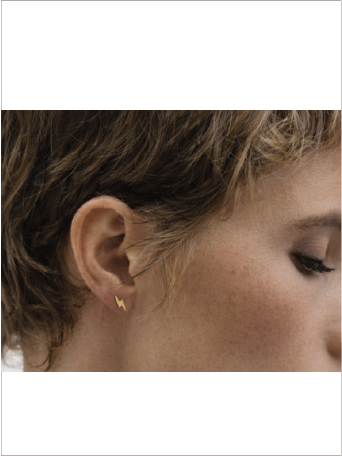 Close-up of a person wearing a gold earring with a plain background