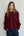 Woman wearing a burgundy sweater with white buttons against a plain background