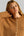 A close-up of a woman wearing a warm camel brown knit cardigan sweater with a button-up front.