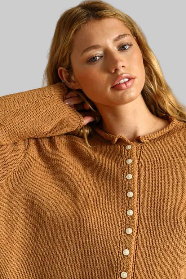 A close-up of a woman wearing a warm camel brown knit cardigan sweater with a button-up front.