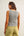 Woman wearing a gray sleeveless top and green pants on a plain background