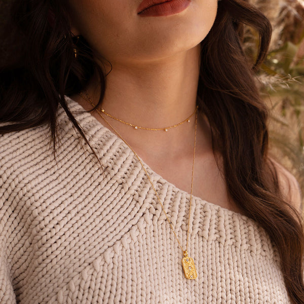 woman with gold necklace and beige sweater