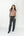 A woman modeling a red and beige striped mock neck knit top with dark gray wide-leg jeans and black pointed-toe boots, standing against a plain white studio background.