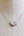 A polished silver heart-shaped pendant necklace displayed on a cream linen mannequin bust.