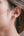 Close-up of an ear wearing a gold earring with small studs.