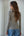 Woman wearing a striped long-sleeve top and blue jeans against a plain background