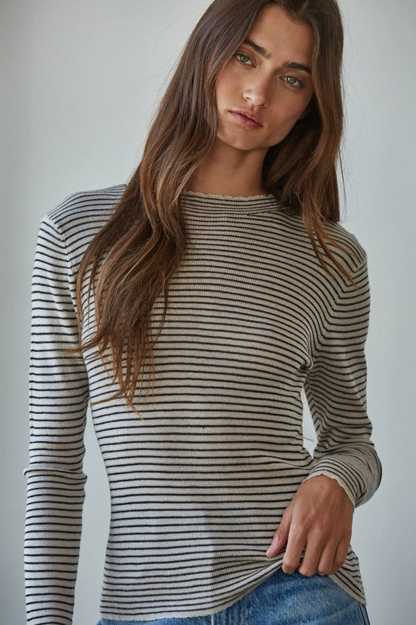 Woman wearing a striped long-sleeve shirt against a plain background