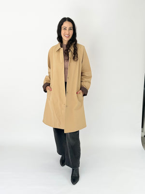 woman in tan trench coat and grey jeans