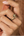 Close-up of a hand wearing a gold ring with a snake design.