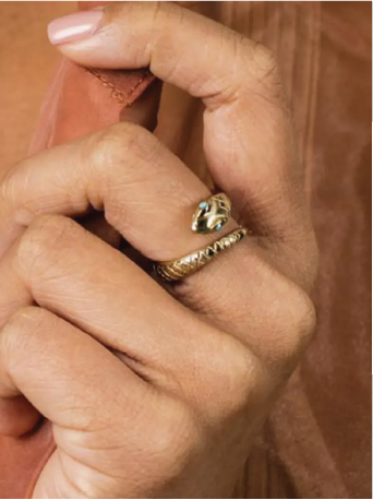 Close-up of a hand wearing a gold ring with a snake design.